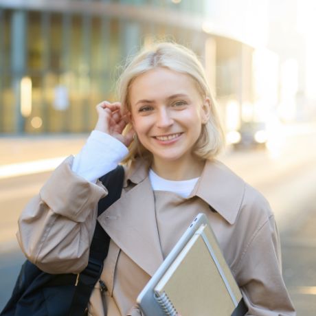 Junge Frau steht vor einem modernen Schulgebäude